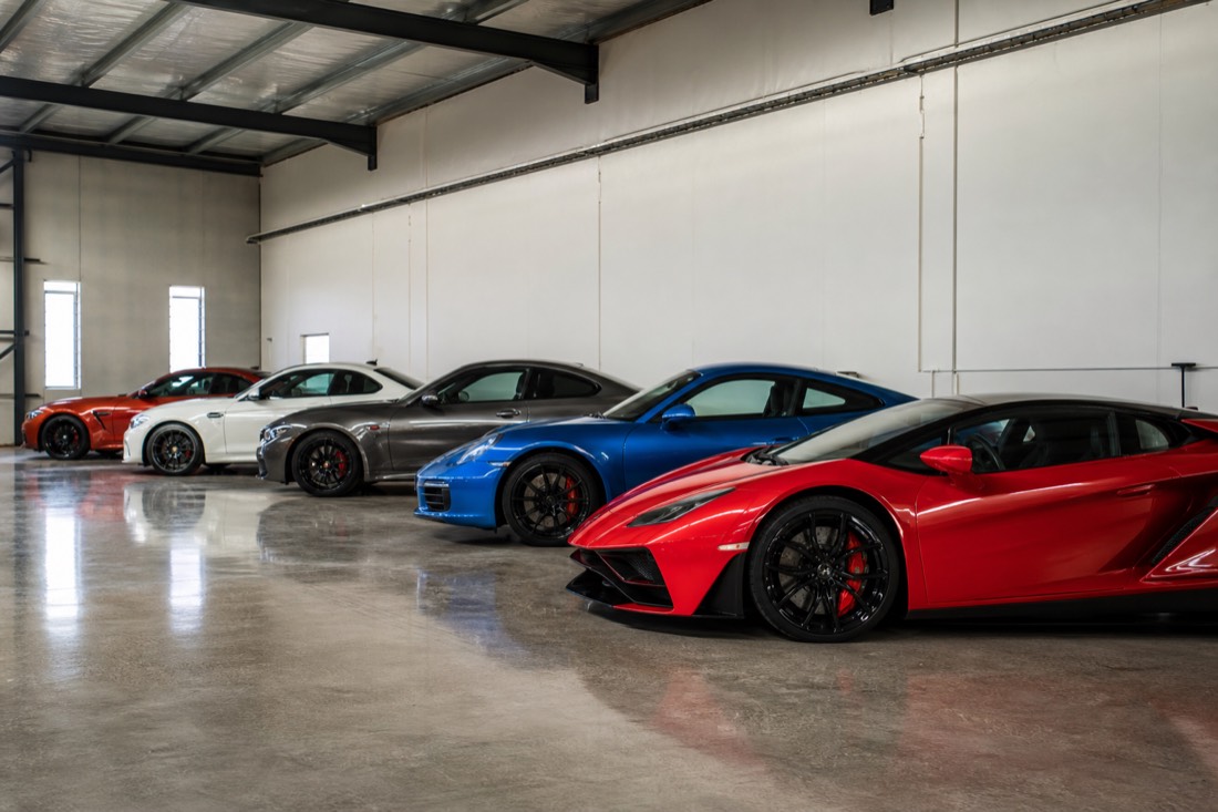 A row of performance cars of varying prestige lined up in a garage